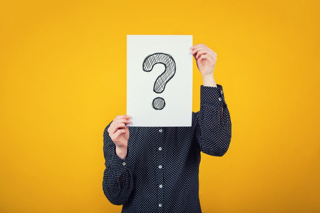 a businessperson holding a white sheet with question mark drawn on it