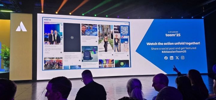 Audience watching a large event screen showing a live social media wall at Atlassian Team '25.